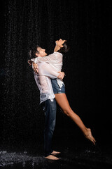 Fototapeta na wymiar wet happy and passionate romantic couple hugging in rain drops on black background