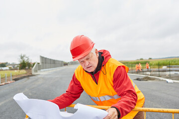 Straßenbauer mit Lageplan auf der Baustelle