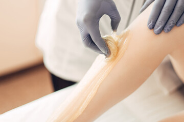 Depilatory master removes hair to the client using sugar paste