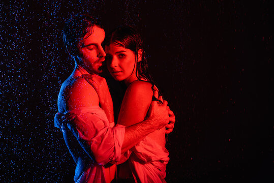 red and blue colors filters picture of wet passionate romantic couple hugging in water drops on black background