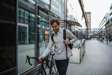 Trendy handsome businessman on city street with his bike