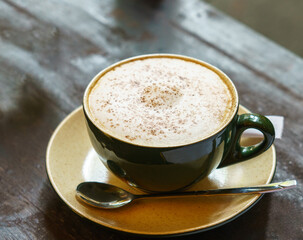 Cappuccino coffee with cacao topping on rustic wooden table