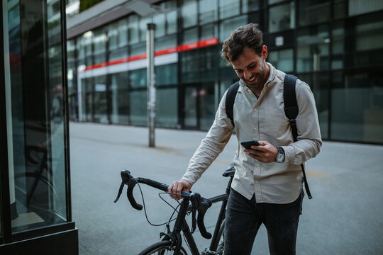 Happy cyclist in the city using phone