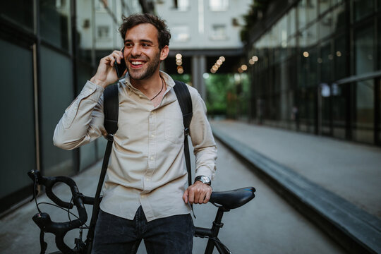 Young businessman with bike using mobile phone