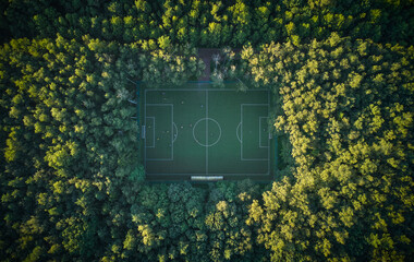 Aerial top down view above the people playing football on a pitch among the forest © mediaeugene