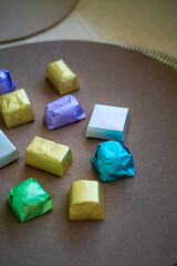 wrapped luxury chocolates in various colours for different flavours on a brown background.