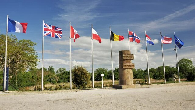 Caen, France May 2021. Film multi-country flags in the wind next to a WWII memorial at Pegasus Bridge in Caen. 4k high definition movie