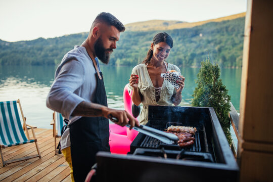 Lovely couple grilling food at barbecue outdoors