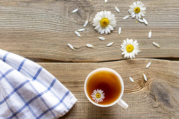 Daisy tea on a wooden table with flowers of daisies lying next to