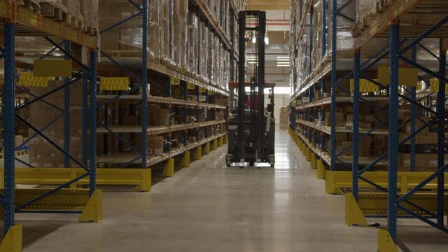 Fork lift driving away through corridor in large shipping warehouse