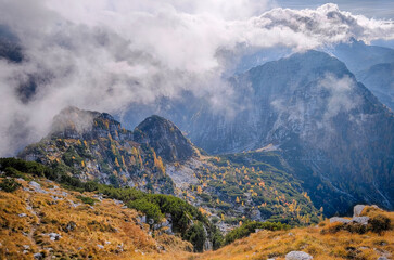 landscape of golden orange and red colors of autumn alps slovenia italy low clouds and first snow bright sunny day