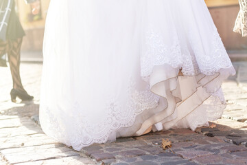 Fototapeta na wymiar Dirty white wedding dress. Elegant bridal gown on the paving stone. The bride drags her celebrating clothing on the ground.