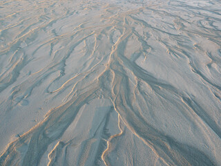 Texture of white sand in the rays of dawn, natural background. Top view of the sandy beach, close-up, copy space