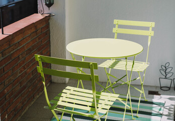 Mesa individual con dos sillas de color verde, sobre una alfombra en un balcon