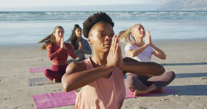 Group of diverse female friends meditating at the beach
