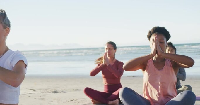 Group of diverse female friends meditating at the beach
