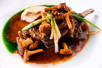 Roasted lamb chops with chanterelles and vegetables on decorated table