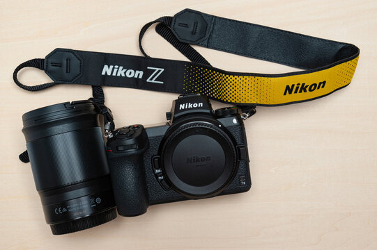 Fuji City, Shizuoka Ken, Japan - May 23, 2021: Nikon Z 7II mirrorless digital camera body with neck strap and lens Nikkor Z 85mm f1.8 S. Isolated on wooden background. Top view.