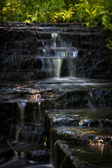 Cascading waterfall cascades in Estonia in green light at summertime