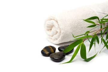 Rolled towel, pebbles and bamboo branch on white background
