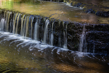 Cascading waterfall cascades in Estonia in green light at summertime