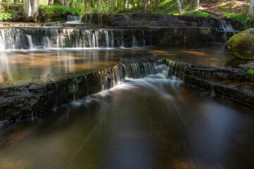 Cascading waterfall cascades in Estonia in green light at summertime