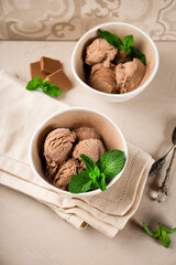 Two bowls with balls of homemade chocolate ice cream with mint vertical photo soft focus