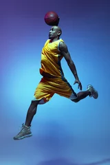 Fotobehang Handsome african-american male basketball player in action and motion in neon light on blue background. Concept of healthy lifestyle, professional sport. © master1305