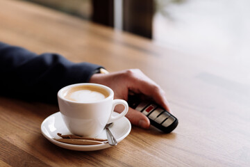 Close view of car keys put on the table next to cup of coffee by rich suited businessman in the cafe. coffee break in cafe or restaurant