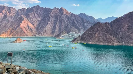 Papier Peint photo autocollant Dubai Hatta Dam Lake in mountains enclave region of Dubai, United Arab Emirates is famous tourist attraction with scenery and place to enjoy kayaking boat ride and other water adventure activities.