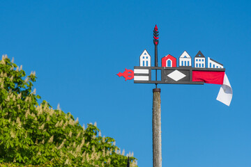 Beautiful colorful weathercock waving in the Curonian Spit in Nida fishermen's village, Lithuania, Europe with blue sky on background 