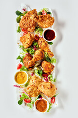 Appetizing fried chicken legs with sauces served on white table