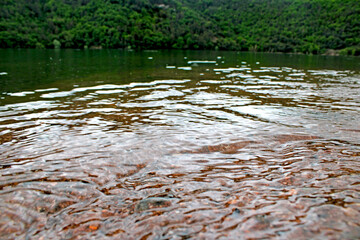 Water flowing over a rock on the shore of a lake