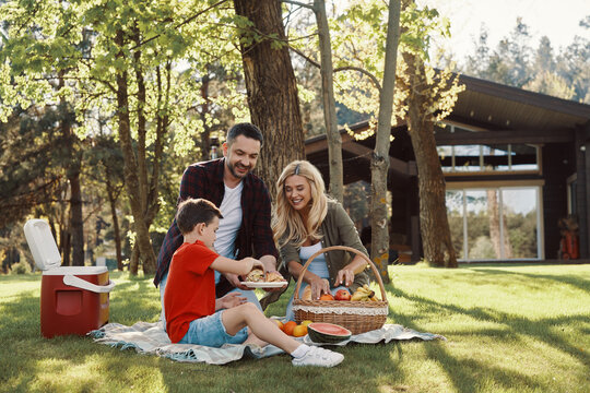 Happy young mother and father with little boy smiling while having picnic outdoors - Powered by Adobe