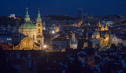 evening view of Charles Bridge and the Church of St. Nicholas in Prague