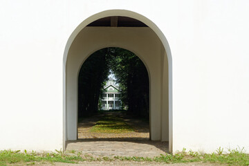 View of the wooden house through the arch of the observation gazebo in the Petrovskoye estate in the Pushkinskie Gory.