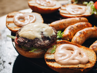 BBQ grilled cheese burgers and sausages on metal grid