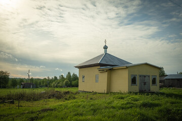 Landscape with a chapel. A small Orthodox church in the village. Church on the green grass. Karelia. Russia.