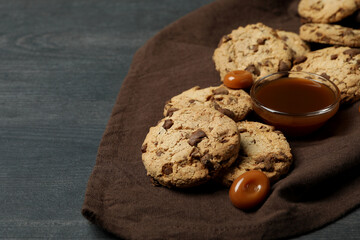 Napkin with cookies and caramel on dark wooden background