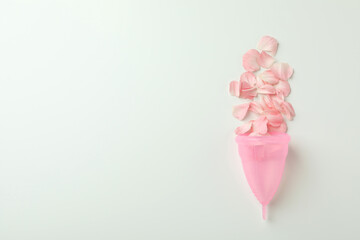 Pink menstrual cup with petals on white background