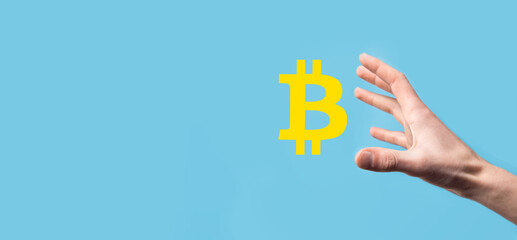 Male hand holding a bitcoin icon on blue background. Bitcoin Cryptocurrency Digital Bit Coin BTC Currency Technology Business Internet Concept.
