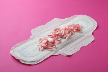 Hygiene pad with petals on pink background