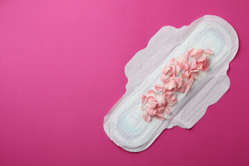 Hygiene pad with petals on pink background