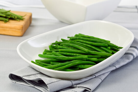 Steamed green beans in white bowl on table