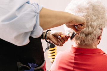 hairdresser combs an elderly woman's hair