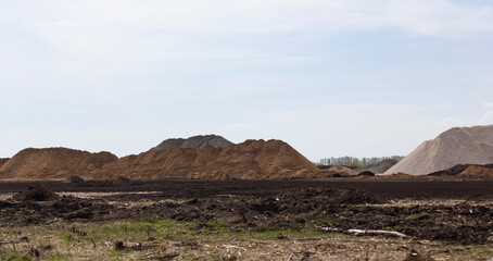 Mountains of sand and rubble. Before starting the construction of a new road. Panorama. The background.