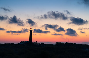 Lighthouse in the dunes and clouds during a nice sunset.