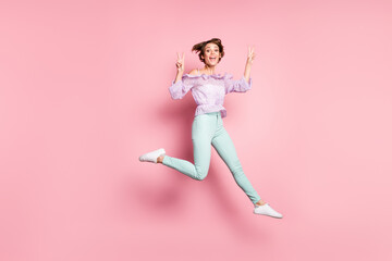 Fototapeta na wymiar Full size photo of young happy charming excited positive girl jumping showing v-sign isolated on pink color background