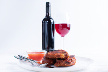 Red wine in glass and roasted tasty meat steaks in plate