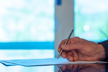 Man signs a document form with a ballpoint pen in the office